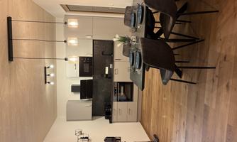 A modern kitchen with a dining area. The table is set for four people and elegant pendant lights hang above.