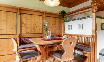 A cozy dining area with wooden paneling and a table. Four chairs surround the table, and decorative plants beautify the space.