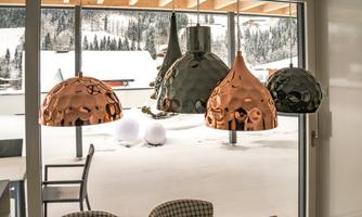 A modern interior view with stylish hanging lamps in various shapes and colors. Outside, there is snow, creating a wintry atmosphere.