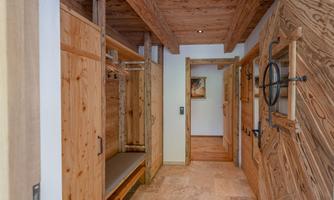 A cozy hallway with wooden walls and doors. The room provides space for storage and an open connection to other areas.