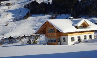 A charming house in the snow with a wooden roof.  
Surrounded by a picturesque winter landscape and snow-covered hills.