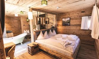 A cozy wooden room with a large double bed and a bathtub. The warm wooden tones create a relaxed atmosphere.