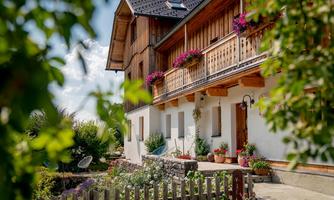 A charming house with wooden cladding, balconies, and blooming plants. The garden is well-maintained and invites relaxation.