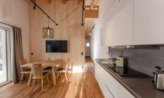 A modern kitchen with a dining table and chairs. The room features wood paneling and large windows that let in plenty of light.