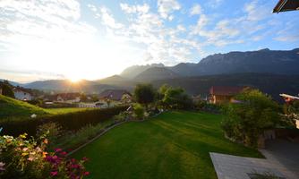 A picturesque landscape with mountains in the background and a sunny meadow in the foreground. The colors of the flowers and the sky create an idyllic atmosphere.