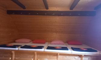 A cozy sleeping area with wooden paneling. There are several sleeping spaces with pillows and blankets.