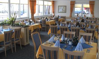 A cozy restaurant with decorated tables in yellow and blue. Large windows ensure plenty of daylight.