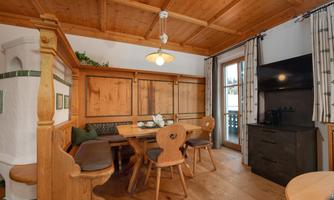 A cozy dining area with wood paneling and a large table. Large windows let in a lot of light and provide a view outside.