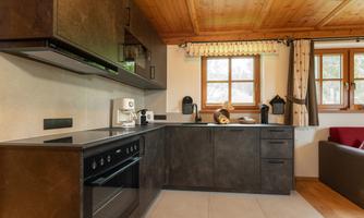 A modern kitchen with dark cabinets and high-quality appliances. Above the countertop are windows that let plenty of light into the room.