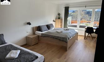 A modern room with two beds and plenty of natural light. The view shows a tranquil landscape through the window.