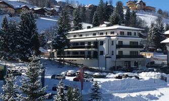 A modern building in the snow with a view of the mountains. Surrounded by snow-covered trees and idyllic winter landscape.