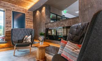 A stylish living room with modern armchairs and wood paneling. The room has large windows and a cozy atmosphere.