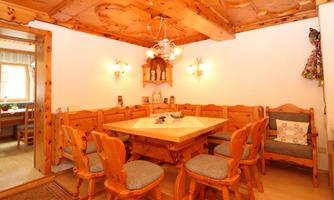 An inviting dining room with paneled wooden walls and a large table in the center. Cozy chairs and soft lighting create a warm atmosphere.