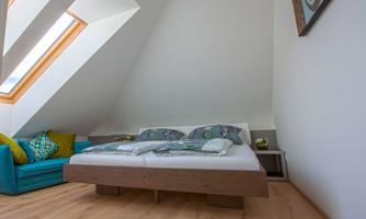 A cozy bedroom with a large bed and colorful cushions. A bright room with skylights and a comfortable couch.