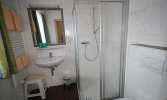 A modern bathroom with a shower cabin, a sink, and a mirror. There are bright tiles and a clean, tidy decor.