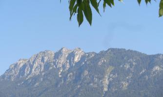 An impressive mountain with clear outlines and green forests. The sky is blue and cloudless.