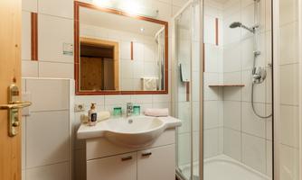 A modern bathroom with a shower and a sink. The walls are brightly tiled and a mirror is located above the sink.