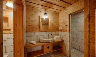 A rustic bathroom with wooden walls and a modern sink. The atmosphere is cozy and inviting.