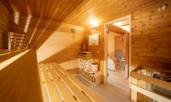 A cozy sauna room with wooden paneling and loungers. The light creates a relaxing atmosphere.