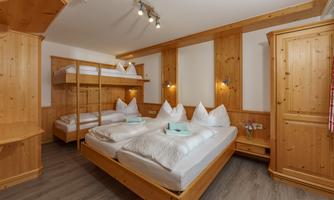 A cozy room with wooden paneling and two bunk beds. There are four single beds and an inviting atmosphere.