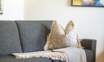 A cozy gray sofa with decorative pillows and a wool blanket.