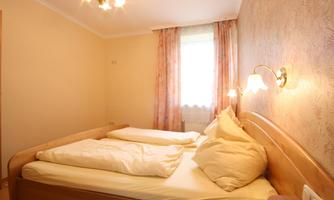 A cozy bedroom with a large double bed and soft colors. The window lets in plenty of natural light, creating an inviting atmosphere.