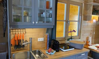 A cozy kitchen with gray cabinets and a wooden table. On the countertop are kitchen utensils and some decorative elements.