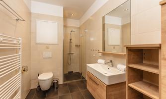 A modern bathroom with a shower and a wooden vanity. The walls are painted in light colors, creating a bright, friendly atmosphere.