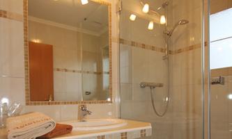 A modern bathroom with a glass shower and a mirror. Fresh towels are ready on the sink.