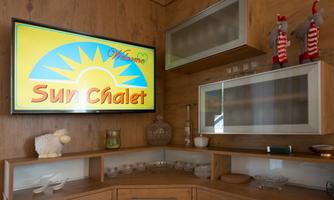 A cozy interior with wooden paneling. A television displays the logo "Sun Chalet" with a sun in the background.