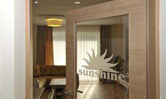 An open door with the inscription "sunshine" and a view of a modern living room. The room is bright and inviting with cozy furniture.