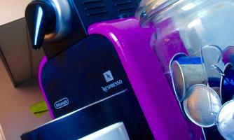 A colorful Nespresso machine stands on the countertop. Next to it is a cup and a glass with coffee capsules.