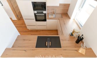 A modern kitchen with wooden countertops and a cooktop in the center. Bright colors and plenty of natural light create an inviting atmosphere.