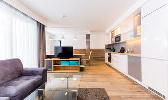 A modern apartment with an open living area. The space is brightly furnished, with a kitchenette and a cozy sofa.