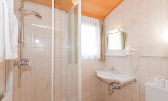 A modern bathroom with a shower and sink. Bright tiles and a wooden ceiling create an inviting atmosphere.
