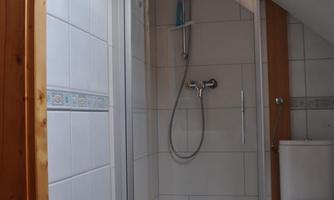 A bathroom with a shower and toilet. The walls are brightly tiled and there are wooden details.