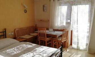 A cozy room with a double bed and a dining area. Large windows let in plenty of light and create an inviting atmosphere.