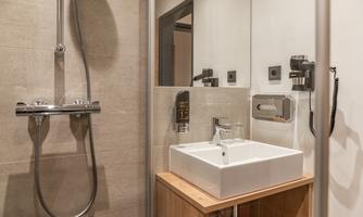 A modern bathroom with a shower and a sink. The walls are bright and the fixtures are functional.
