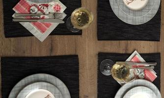 An elegantly set table with four places. The plates feature a stylized reindeer motif, along with glasses and napkins in festive colors.