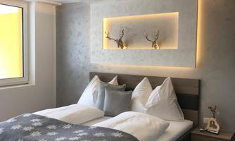 A modern bedroom with a large bed and stylish pillows. Soft light and minimalist decoration create an inviting atmosphere.