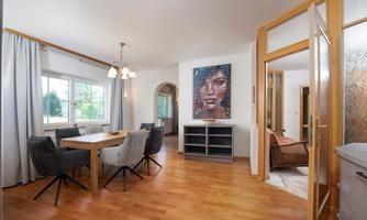 A bright and inviting dining room with a large table and comfortable chairs. A striking piece of artwork hangs on the wall.