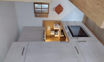 A modern kitchen with light wood cabinets and a stove. On the countertop, there is a coffee machine and a kettle.