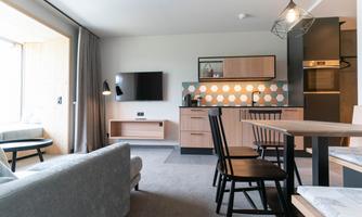 A modern apartment with an open kitchen and a cozy living area. Bright colors and large windows create an inviting atmosphere.