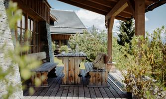 A cozy terrace with wooden furniture and a view of the green landscape. Surrounded by plants and an inviting atmosphere.