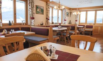 A cozy restaurant with wooden paneling and large windows. The tables are neatly set, creating an inviting atmosphere.