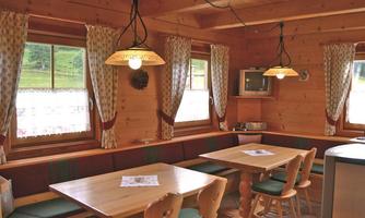 A cozy room with wooden furniture and large windows. The atmosphere is warm and inviting, ideal for social gatherings.