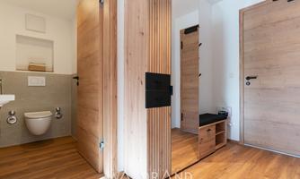A modern designed bathroom with wooden details and a warm flooring. The walls are clear and bright, giving the space an inviting atmosphere.