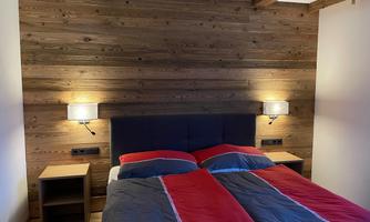A cozy bedroom with a double bed and nightstands. The walls are paneled with wood and there is soft lighting.