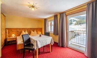A cozy room with a table and chairs.  
Large windows offer a beautiful view of the mountains.