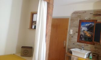 A simple room with a bed, a partition, and a sink. It has a friendly atmosphere with bright colors.